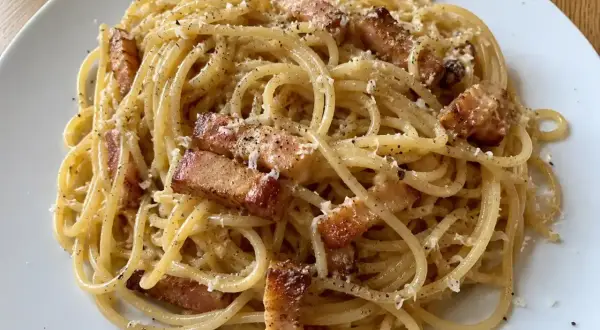 En portion riktig carbonara med spaghetti, knaprigt sidfläsk och rikligt med parmesanost.