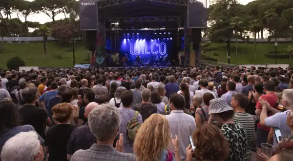 Gran concierto de Wilco en el **jardín de invierno Zaragoza**. Multitud disfruta al aire libre bajo un cielo crepuscular.