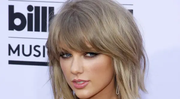 Taylor Swift mit festlichen Frisuren kurze Haare, blauen Augen und einem leichten Lächeln.