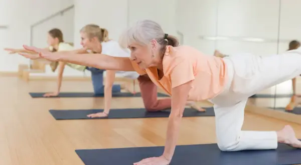 Des seniors en pleine forme sur un tapis, pratiquant un exercice de **parcours équilibre senior**.