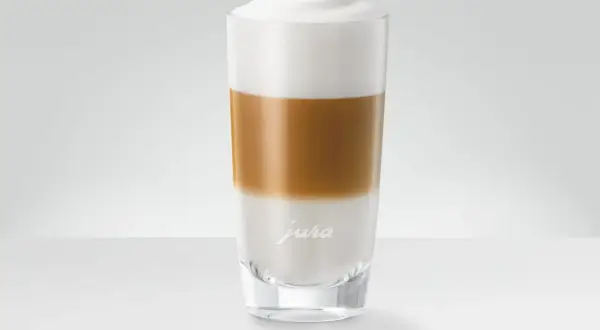 En hög latte macchiato med lager av mjölk och kaffe, toppad med ett fluffigt skum.