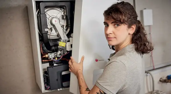 Une technicienne installe une chaudière F28. Elle tient le panneau avant ouvert, révélant les composants internes.