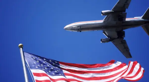 Samolot przelatuje nad flagą USA. Zastanawiasz się, ile trwa lot z Warszawy do Los Angeles?