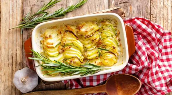 Gratin de pommes de terre et courgettes, une idée pour cuisiner la pomme de terre en 45 recettes originales. Servi avec du romarin et de l'ail.