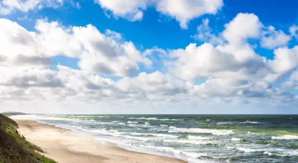 Plaża nad Bałtykiem, falujące morze i błękitne niebo z chmurami. Trudno oszacować, ile wody jest w Bałtyku, ale jest jej mnóstwo!