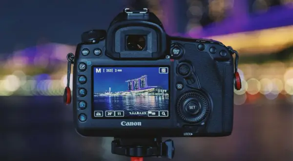 Aparat Canon z ekranem pokazującym nocną panoramę miasta. Dowiedz się, jak robić zdjęcia w ciemnych pomieszczeniach bez lampy, wykorzystując ustawienia aparatu.