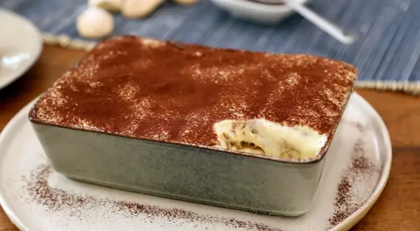 Un délicieux tiramisu pour 4 personnes, saupoudré de cacao, prêt à être dégusté.