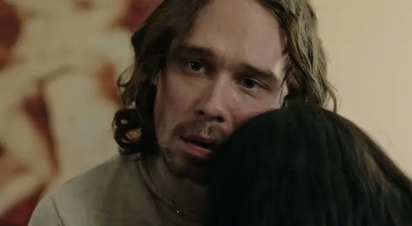 En man med långt hår och blå ögon kramar någon i tv-serien "Rollistan i Knutby".