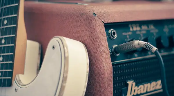 Biała gitara elektryczna podłączona do wzmacniacza Ibanez. Idealny zestaw do nauki gry na gitarze elektrycznej.