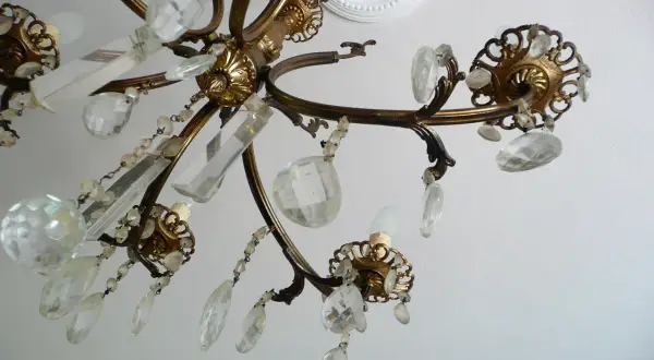 Dettagli di un lampadario a gocce in ottone, con cristalli trasparenti e perline. Un'idea per come rimodernare un lampadario a gocce con un tocco di eleganza.