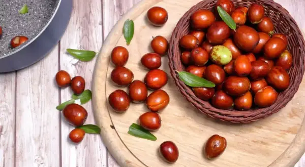 Giuggiole rosse e verdi in un cesto e sparse su un tagliere. Scopri quante calorie hanno le giuggiole per uno snack salutare.