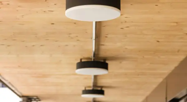 Nowoczesne lampy, każdy plafon ścienny z czarną obudową i białym dyfuzorem, zamontowane na drewnianym suficie.