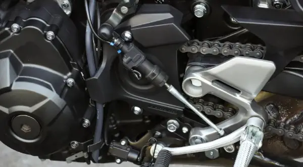 Zbliżenie na mechanizm quickshiftera motocyklowego z łańcuchem napędowym.