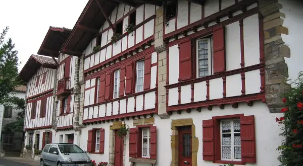 Maison basque typique, peut-être l'origine du nom Ithurburu. Volets rouges, colombages blancs, une voiture garée.