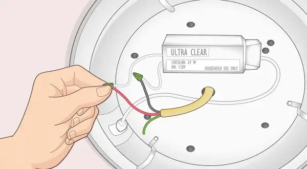 Main d'une personne effectuant le branchement d'un éclairage, connectant un fil rouge à un connecteur vert.