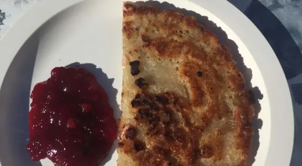 En gyllene kolbulle med lingonsylt på en vit tallrik. Perfekt för ett enkelt kolbulle recept.