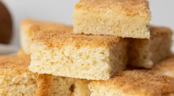 Stapel von saftigen Buttermilch Kokos Kuchenstücken, goldbraun gebacken und mit Kokosraspeln bestreut.
