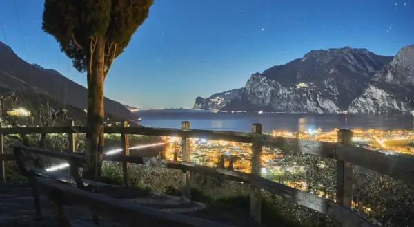 Vista notturna di Riva del Garda, con luci scintillanti e montagne sullo sfondo. Perfetto per scoprire cosa fare la sera.