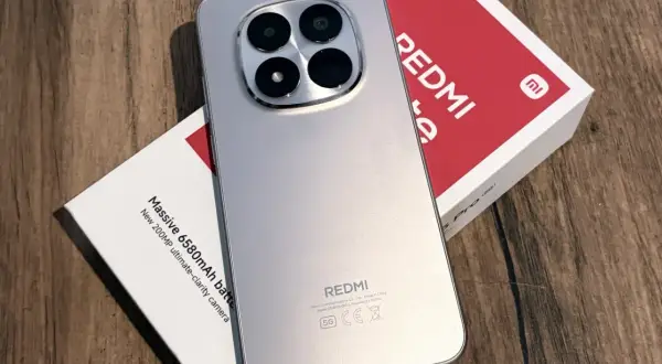 Srebrny, najnowszy Redmi z imponującym aparatem 200MP i baterią 6580mAh, leżący obok swojego czerwono-białego pudełka.
