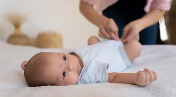 Malutkie dziecko leży na białym tle. Mama przygotowuje się do szczepienia RSV w ciąży, dbając o bezpieczeństwo maluszka.