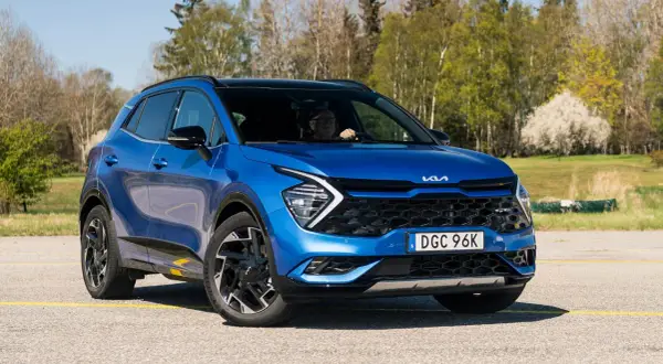 Blå Kia Sportage, en begagnad bil som testas i soligt vårväder.