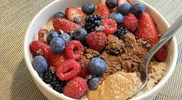 Schüssel mit overnight oats mit proteinpulver, Beeren, Kakao und Erdnussbutter.