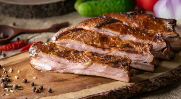 Soczysty, pieczony boczek na desce z przyprawami i papryczkami chili.