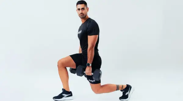 Uomo con manubri esegue affondi, un esercizio che rientra nel concetto di amrap significato: "as many reps as possible".