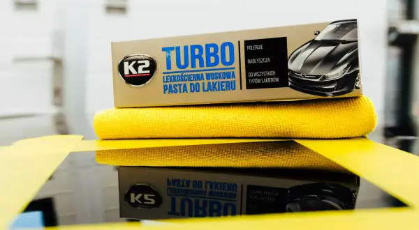 K2 Turbo pasta do lakieru samochodowego na żółtej mikrofibrze, gotowa do polerowania.