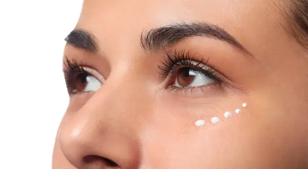 Application de crème hydratante en points sur le coin interne de l'œil pour un maquillage lumineux.