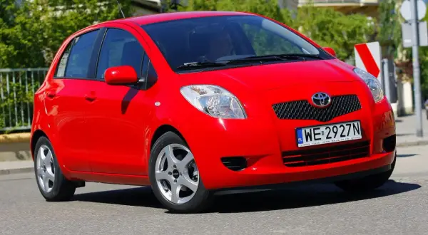 Czerwony Toyota Yaris 2008 z polskimi tablicami rejestracyjnymi WE 2927N jedzie po ulicy.