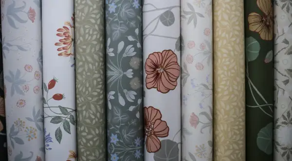 Rullar med vackra tapeter i olika mönster, inspirerade av naturen. Här finns blommor, blad och bär i harmoniska färger. En av tapeterna visar ett mönster av Hanna Wendelbo.