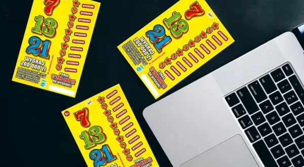 Zdrapki z numerami 7, 13, 21 leżą obok laptopa. Czy można wygrać w zdrapki grając wyłącznie w te same numery losów?