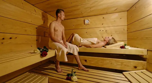 Ein Paar entspannt sich in einer Sauna. Vielleicht ist dies ein Teil eines **Bauernhofs in den Bergen**, wo man nach einem aktiven Tag in der Natur zur Ruhe kommen kann.
