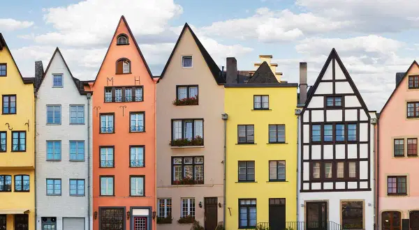 Bunte hausfassade farbe beispiele: Gelb, Weiß, Orange, Beige, Gelb, Weiß und Rosa Häuser reihen sich aneinander.