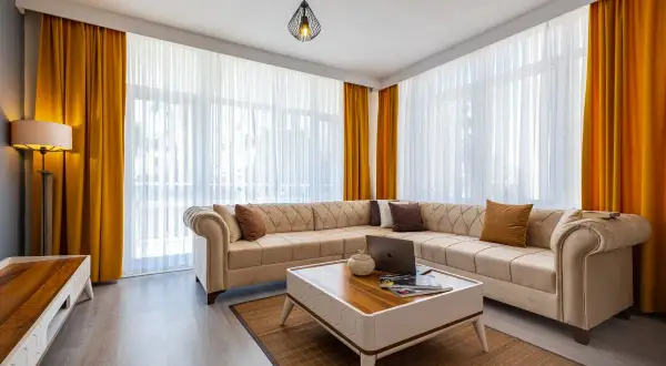 Jasny salon z beżową kanapą i żółtymi zasłonami. Dowiedz się, jak prać zasłony welurowe, by wyglądały jak nowe.