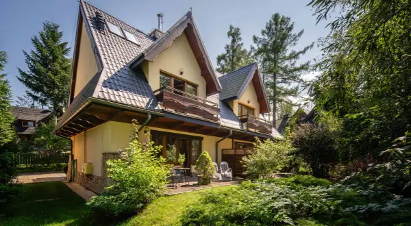 Urokliwy pensjonat w Zakopanem, z widokiem na Giewont. Dom otoczony zielenią, z drewnianymi balkonami i tarasem.