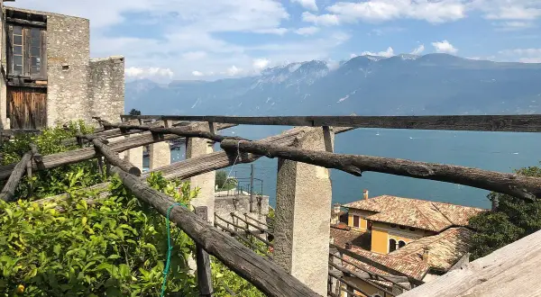 La **limonaia la malora** domina il lago, con le sue strutture in legno e le montagne sullo sfondo.