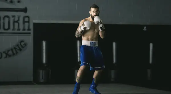 A boxer, ready to fight, demonstrates his switch hitter stance in a boxing gym.