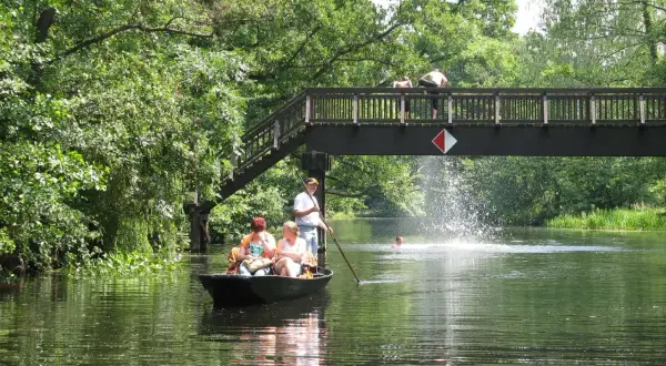 Bootsfahrt im Spreewald: Familie genießt die Natur, während jemand unter der Brücke schwimmt. Perfekte Ausflugsziele Spreewald für einen Sommertag.