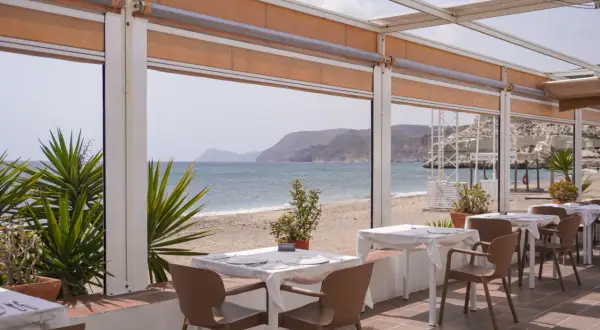 Mesas listas para cenar en el asador La Chumbera, con vistas al mar y la playa.