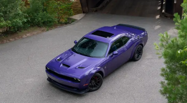 Fioletowy Dodge Challenger z czarnym spojlerem i szyberdachem, idealny na letnie przejażdżki. Sprawdź dodge challenger cena!