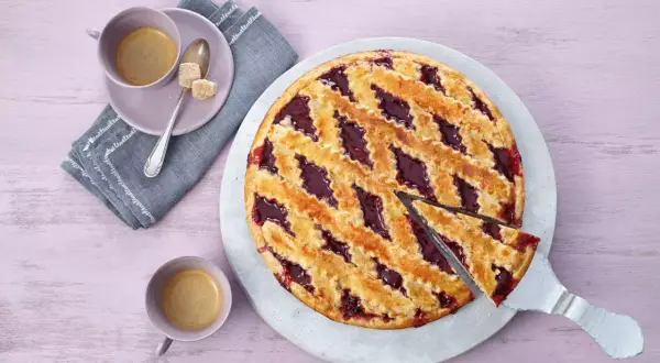 Ein köstliches Linzer Torte Rezept: goldbrauner Teig mit fruchtiger Marmelade, serviert mit Kaffee.