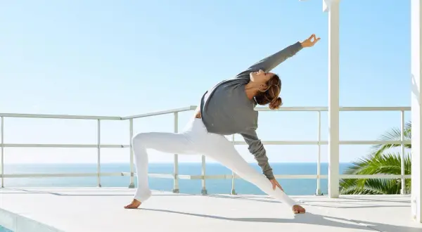 Mujer en postura de yoga expansiva, reflejando la esencia de jivamukti yoga que es.