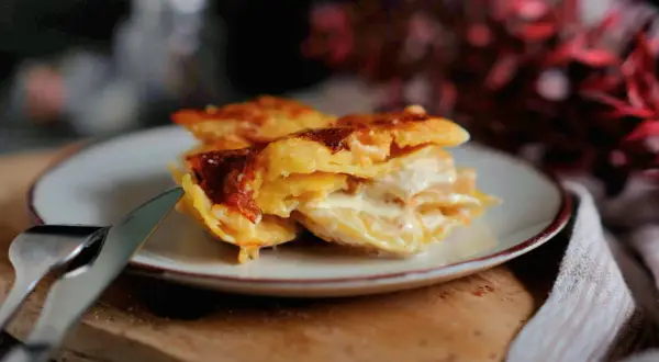 Ein Stück cremiges Kartoffelgratin mit goldbrauner Kruste auf einem Teller, bereit zum Genießen. Dieses Kartoffelgratin Rezept ist ein Genuss!