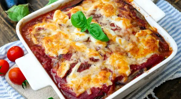 Herzhaftes Parmigiana di melanzane, überbacken mit geschmolzenem Käse und garniert mit frischem Basilikum.