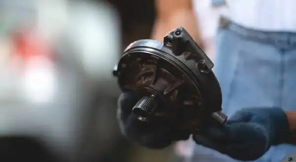Mechanik pokazuje element pompy wspomagającej hamulce, wyjaśniając, jak działa serwo hamulcowe.