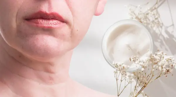 Un vasetto di crema e fiori secchi accanto al viso di una donna, suggerendo come migliorare la pelle del viso con prodotti naturali.