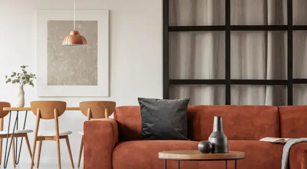 Gemütliche Wohnung inspo: Orange Couch, Holztisch mit Stühlen und ein kupferfarbener Lampenschirm.