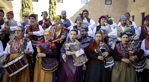 Grupo de gaiteros y músicos celebran el día San Jorge Zaragoza, con trajes tradicionales y diversos instrumentos.